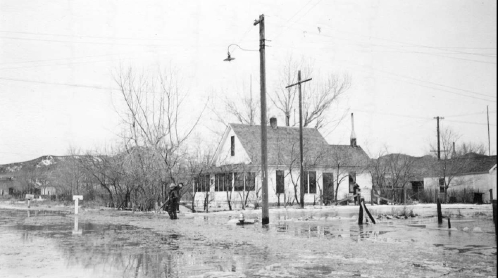 image054s.jpg - 1944. Charles & Victoria Kaiser's home after the flood. Charles carries grandson, Bruce Davis.