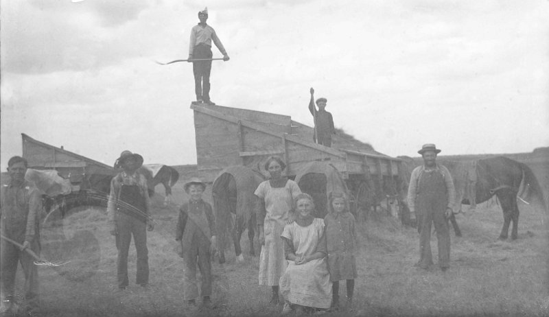 zeltinger007.jpg - Glass plate negative of Tolley, ND havest; from Mathias Zeltinger estate; Matt Zeltinger in overalls and holding pitch fork far left; man to far right is Ignatius Zeltinger standing by the horse. Young man standing in the wagon is Frank Zeltinger. The 3 girls are probably Lena Zeltinger standing, Louise Zeltinger seated, and Clara Zeltinger beside her; others are unknown. Frank, Jr. stated, "They would go over to this land about 3 miles away for harvest and camp there for a while instead of driving the horses back & forth."