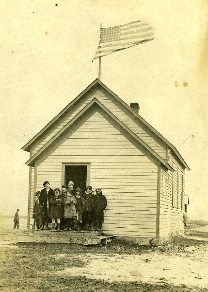 zeltinger024.jpg - Photo from Laura and Matt Zeltinger's estate. One room school house, Tolley, ND. The school was known as the Zeltinger school, as it was on land donated by John Zeltinger.  It stood on top ot the hill derelict until about 2000.  It was a real landmark. Ignatius Zeltinger's daughter, Lena (Zeltinger) Resch is the teacher on the left. Lena taught there for at least two years. Lena's sister, Marie Zeltinger, is standing next to her, and another of Lena's sister, Otillie "Tillie" Zeltinger, is the middle girl in the front. See next photo for closeup.