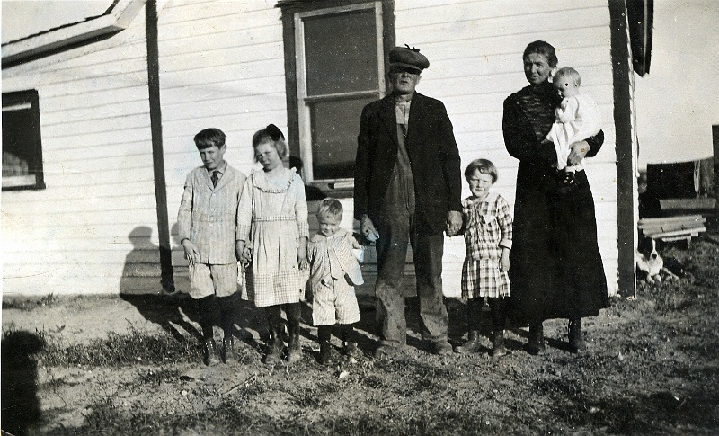 jz_092.jpg - Jensen family poses in front of a painted house; the reverse inscribed, "To Grandma and Grandad From Helen Jensen." Note that Magdelena "Kate" Zeltinger (sister to Ignatius and John Zeltinger) married Jens C. "Jim" Jensen, and they lived in the Norma, ND area before homesteading in Montana in 1914.